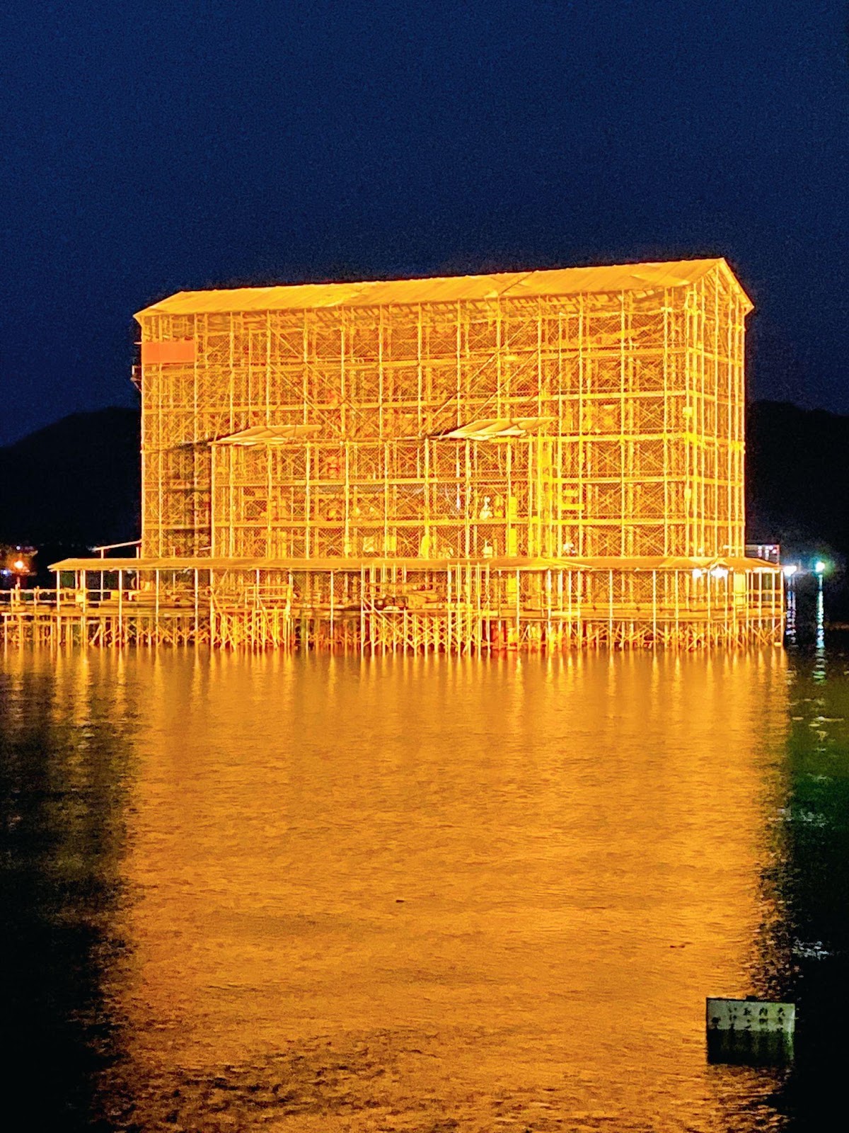 改修工事の足場に覆われ、夜にライトアップされた厳島神社の大鳥居